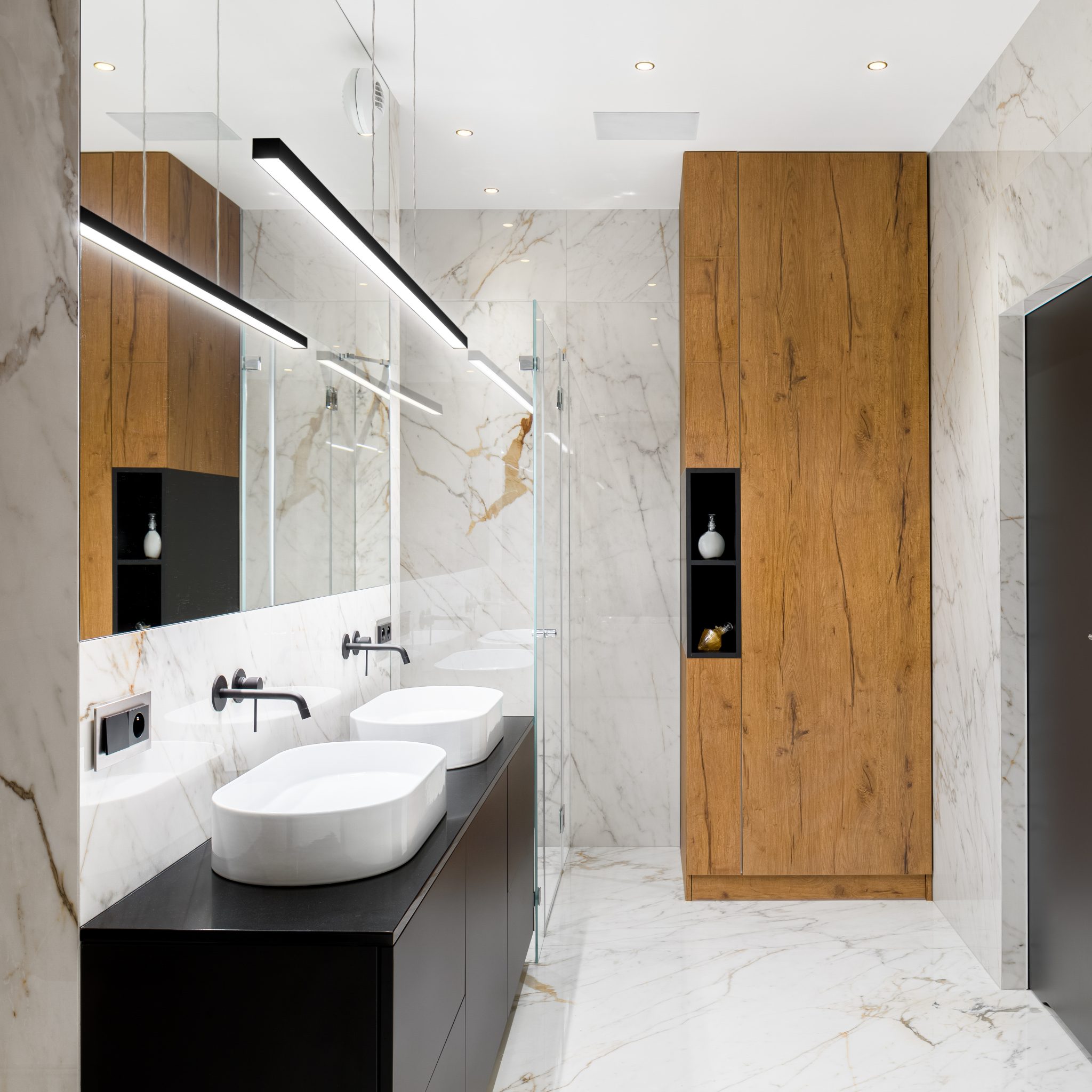 Luxury bathroom with marble tiles on floor and walls, two washbasins and wooden closet